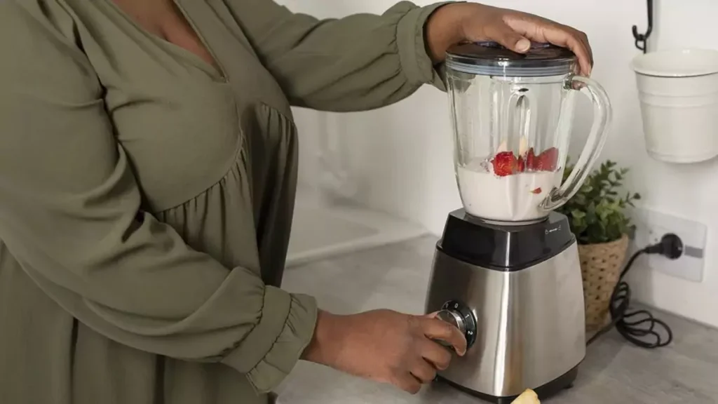 Pessoa fazendo suco com liquidificador com copo de vidro