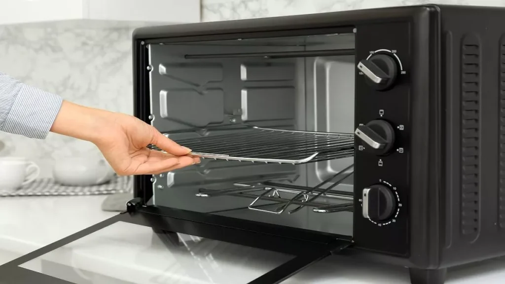 Mão retirando grelha de dentro de forno elétrico