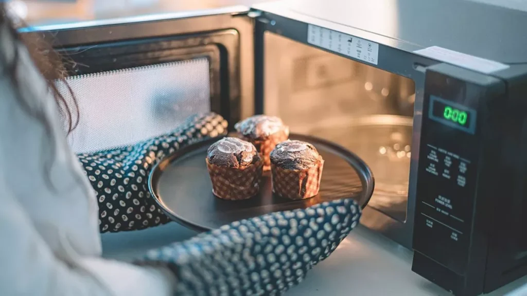 Mulher colocando bolinhos em microondas