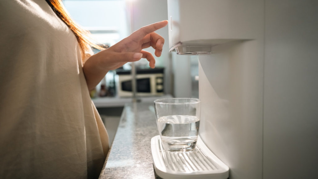 Mulher manipulando purificador de água em cozinha