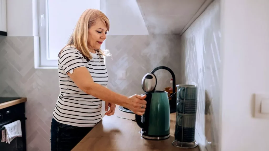 Mulher fervendo água com chaleira elétrica