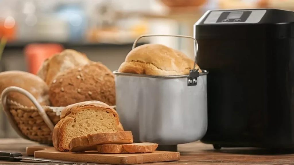 Panificadora ao lado de pães caseiros em mesa de jantar